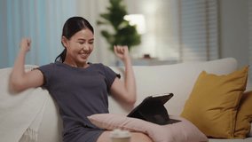Asia people young fan woman laugh smile joy arms raised exult fun bet on online game race sitting relax easy on sofa home at night. Soccer team win goal score in sports match live on digital tablet. - Powered by Shutterstock - Get 15% off with code: PIKWIZARD15