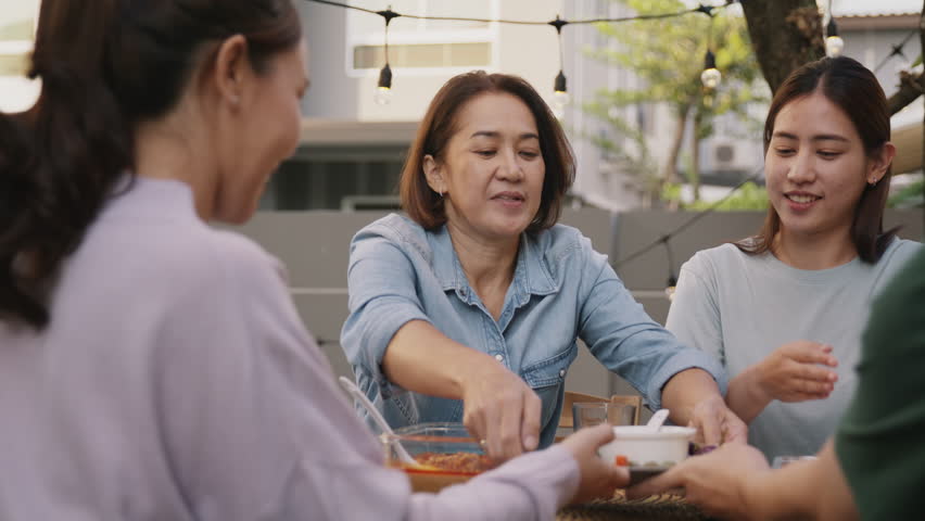 Mom enjoy cooking for family day dining at dine table cozy patio front yard home. Mum passing food serving drink to group four asia people young adult man woman friend fun joy relax warm picnic eating | Shutterstock HD Video #1100186763