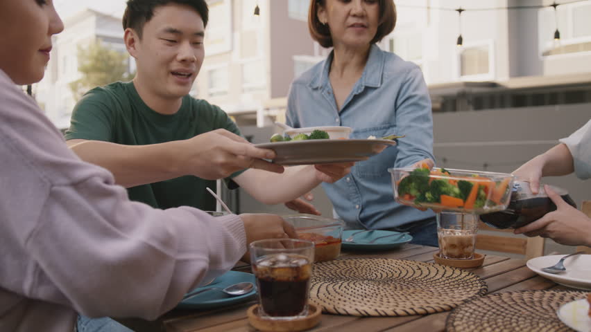 Mom enjoy cooking for family day dining at dine table cozy patio front yard home. Mum passing food serving drink to group four asia people young adult man woman friend fun joy relax warm picnic eating | Shutterstock HD Video #1100186767