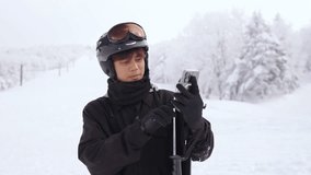4K Young Asian man using mobile phone with internet live streaming online network app or social media during do extreme sport training skiing on snow mountain at ski resort on winter holiday vacation.