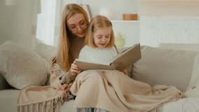 Caring single parent Caucasian mother babysitter mom hug little preschool child girl kid daughter covered with blanket sit on couch learn read book fairy tale story bonding family education at home - Powered by Shutterstock - Get 15% off with code: PIKWIZARD15