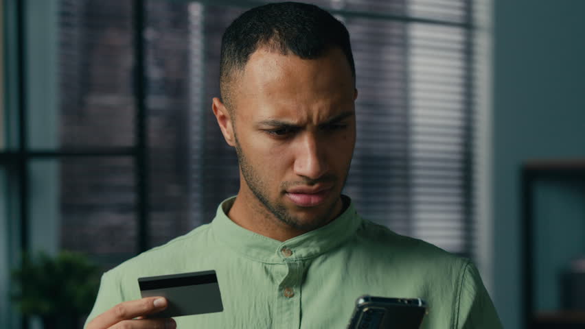 Confused puzzled african american man hold credit card try to pay using mobile banking app on phone payment error online money transfer problem blocked financial limit unsuccessful finance transaction Royalty-Free Stock Footage #1100187115