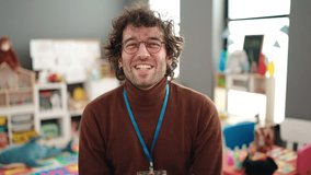 Young hispanic man preschool teacher smiling confident speaking at kindergarten