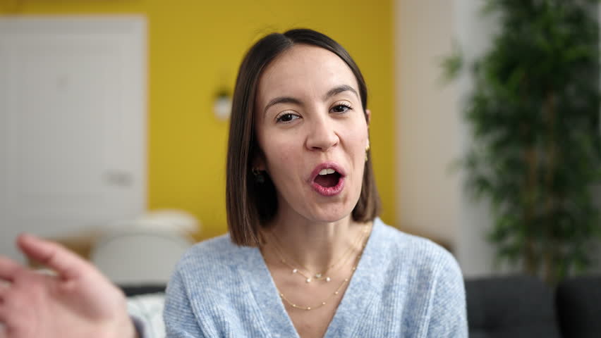 Young beautiful hispanic woman having video call sitting on sofa at home | Shutterstock HD Video #1100190125