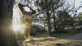 Bottom view young woman in sport suit practice aero-yoga exercise, meditate in lotus pose hanging on ropes upside-down on tree branch against green bushes in bright backlit, wide angle - Powered by Shutterstock - Get 15% off with code: PIKWIZARD15