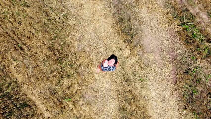 Aerial Drone view Young woman standing and dance on a wheat field with sunrise on the background
