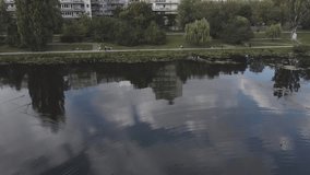 Drone video of lake and forest with building and trees, cloud reflections on lake
