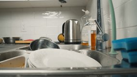 Male housewife washes a plate under running water in the sink in a modern kitchen. slow motion video of housewife using natural dishwashing detergent