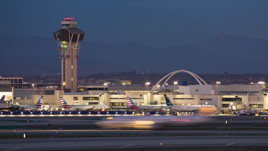 LOS ANGELES, CA - 2023: LAX International Airport Iconic Tower and Theme Building Landmarks Landscape Night Timelapse with Jet Airliners Parked at Terminal Gates and Arriving and Departing Aircraft