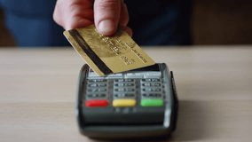 Closeup contactless plastic card transaction on bank wireless terminal. Unknown man making cashless payment using nfc technology. Male hand paying bill touching electronic pos reader with credit card. - Powered by Shutterstock - Get 15% off with code: PIKWIZARD15
