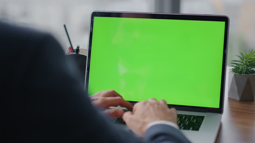 Unknown entrepreneur typing on mockup laptop at office table close up. Businessman chatting at chroma key computer wearing elegant suit. Busy manager using green screen notebook in company work. | Shutterstock HD Video #1100195917