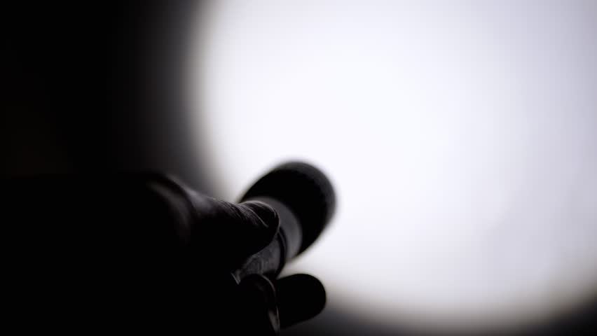 Person Shines a Flickering Flashlight on Wall in a Dark Room. Silhouette of a hand with a flashlight. Abstract shimmering, flashing, pulsing glare beam of light. Spot. Strobe effect. Shadow. Police. | Shutterstock HD Video #1100197273