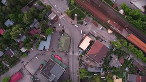 The movement of people and cars next to a small railway station from a bird's eye view.