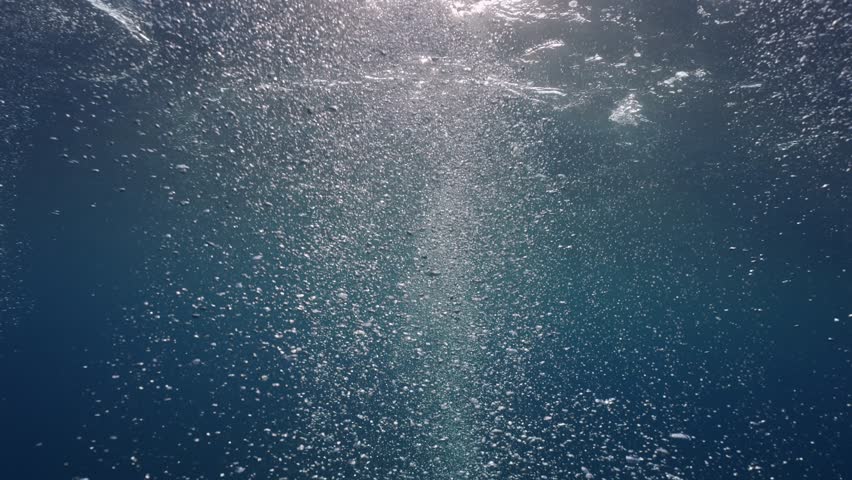 Motion of air bubbles rise up to the surface in blue water, Close-up. Sunbeams and bubbles underwater, slow motion. | Shutterstock HD Video #1100200165