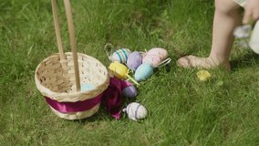 Easter Egg Hunt tradition: kid boy picking up colorful eggs from green grass put them into basket. Child boy gently holding first spring flowers in hand put colorful Easter eggs into basket. sunny day - Powered by Shutterstock - Get 15% off with code: PIKWIZARD15