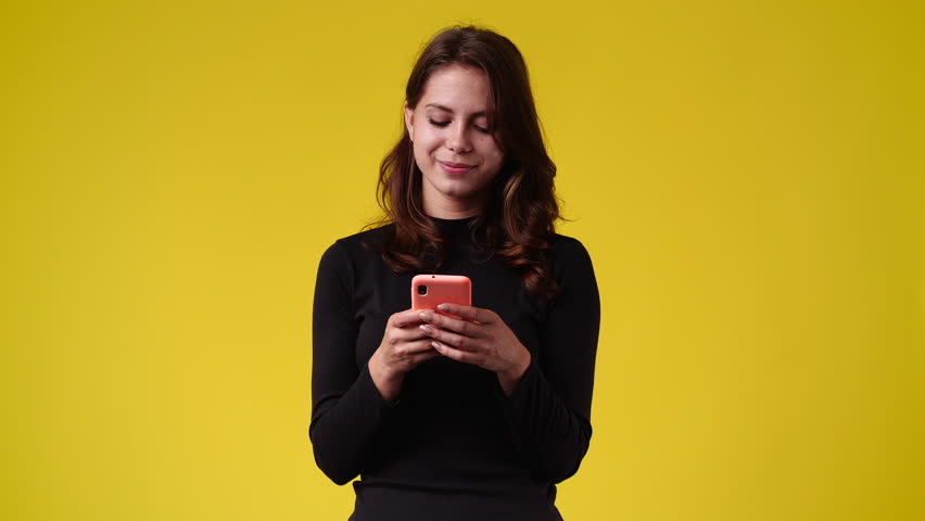 4k video of one woman typing text and looking up on yellow background. | Shutterstock HD Video #1100200837