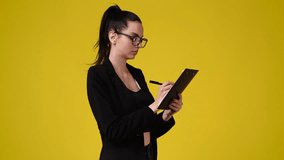 4k video of one girl which notes something with a pen on tablet over yellow background.