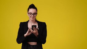 4k video of one girl who looks at the phone and talking to someone over yellow background.