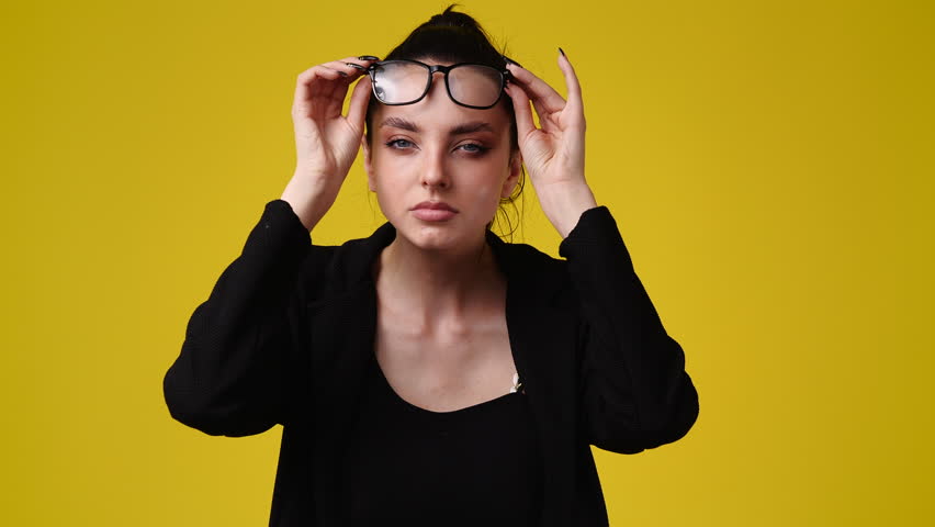4k video of one girl takes off his glasses and tries to see something over yellow background. | Shutterstock HD Video #1100200857