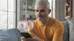 Mature man using smartphone augmented reality dating app,adult male sits on couch uses smart phone browsing women profiles flirting on meeting site application searching for love - Powered by Shutterstock - Get 15% off with code: PIKWIZARD15