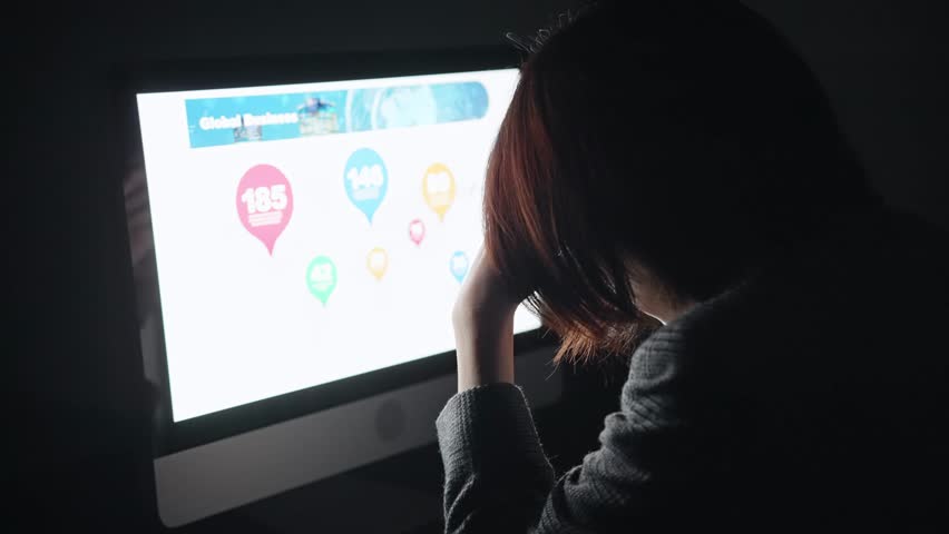 A worried woman looking at a computer screen in a dark room. | Shutterstock HD Video #1100201783