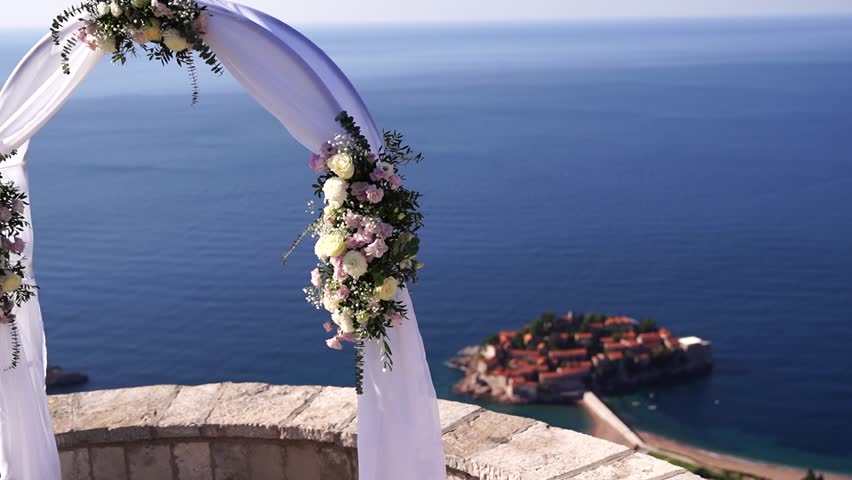 Wedding arch stands on an observation deck overlooking the island of Sveti Stefan