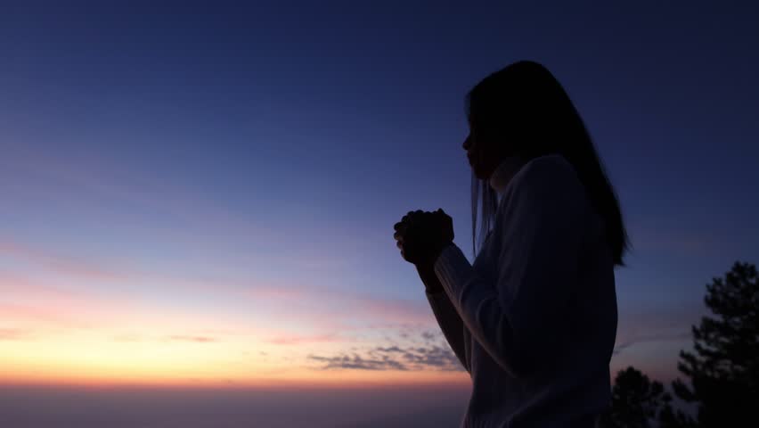 A silhouette of a woman is praying to God as the sun is about to rise.May God protect you and your family.We praise and have faith in God.4K slow motion. Royalty-Free Stock Footage #1100208933