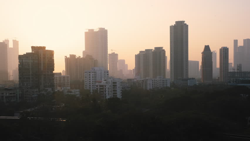 Glowing orange sun setting behind city buildings in silhouette. Colorful sunset behind the high-rise building and skyscrapers of the Mumbai city skyline in India. Timelapse video Royalty-Free Stock Footage #1100209105