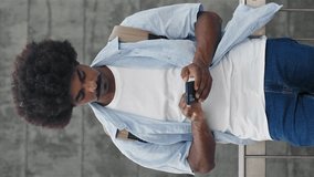Young African American Man man using smartphone cell phone - vertical video - Powered by Shutterstock - Get 15% off with code: PIKWIZARD15