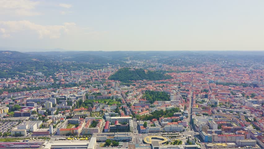 Inscription on video. Graz, Austria. The historic city center aerial view. Mount Schlossberg (Castle Hill). Arises from blue water, Aerial View