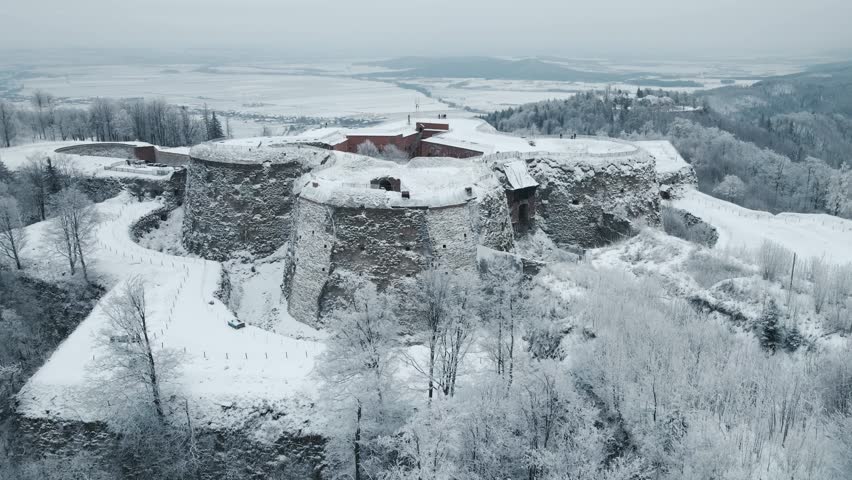 Silver mountain fortress in Poland, Lower Silesia. Winter landscape. 
Frozen trees. Snowy and foggy weather. Drone Footage