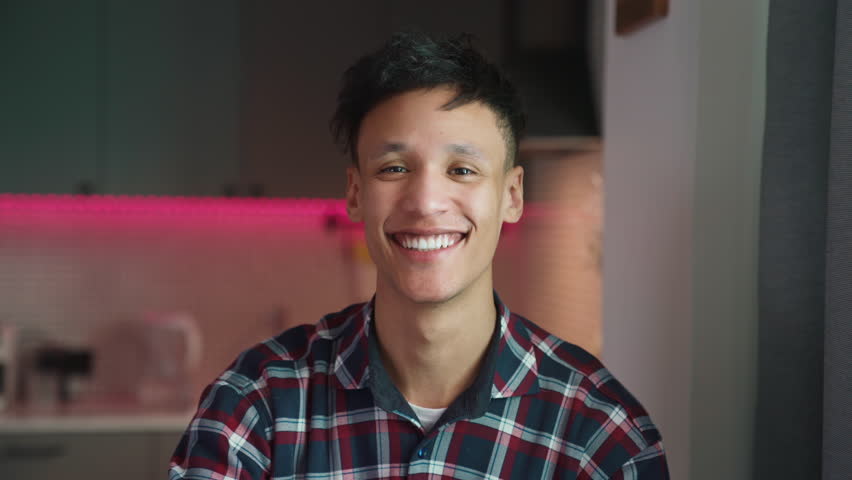 Happy millennial biracial man looking at camera and smiling. Closeup portrait of good looking guy posing alone at home standing in modern designer kitchen. Cheerful lifestyle concept 4k | Shutterstock HD Video #1100217837