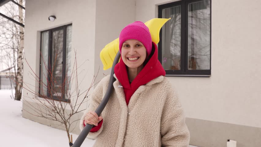 Portrait of a girl with a shovel in winter on the background of a house