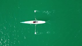 Aerial drone bird's eye view video of sport canoe operated by young woman in emerald clear waters