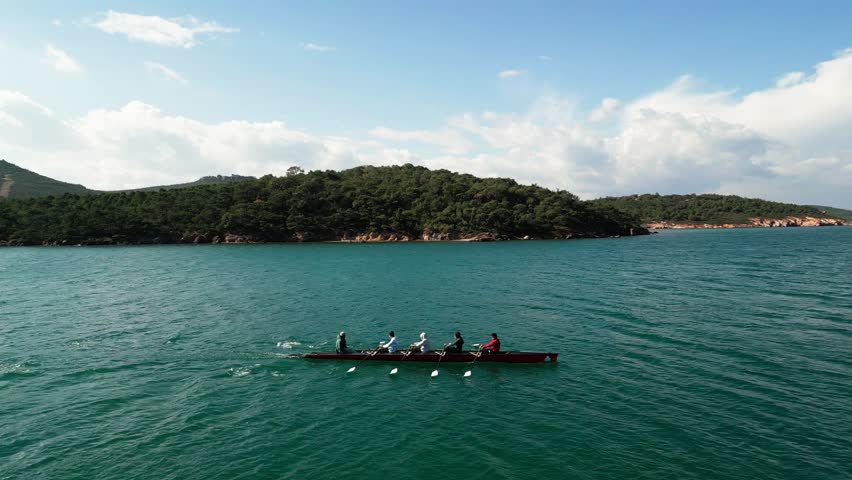 Sport Canoe with a team of four people rowing on tranquil water, Aerial view.