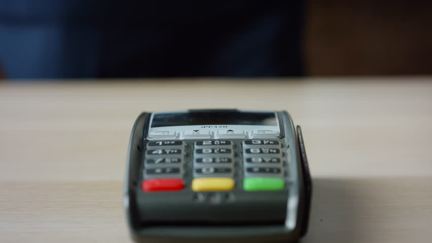 Man hands making contactless payment with credit card at machine terminal on table close up. Unknown client paying bill by touching card to wireless reader bank pos device. Cashless nfc technology. Royalty-Free Stock Footage #1100218759