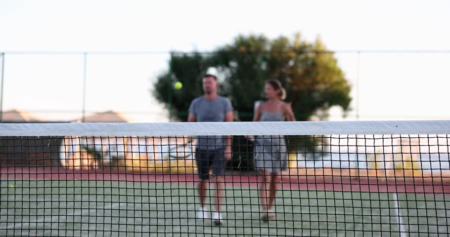 Two friends, man and woman, are walking along tennis court