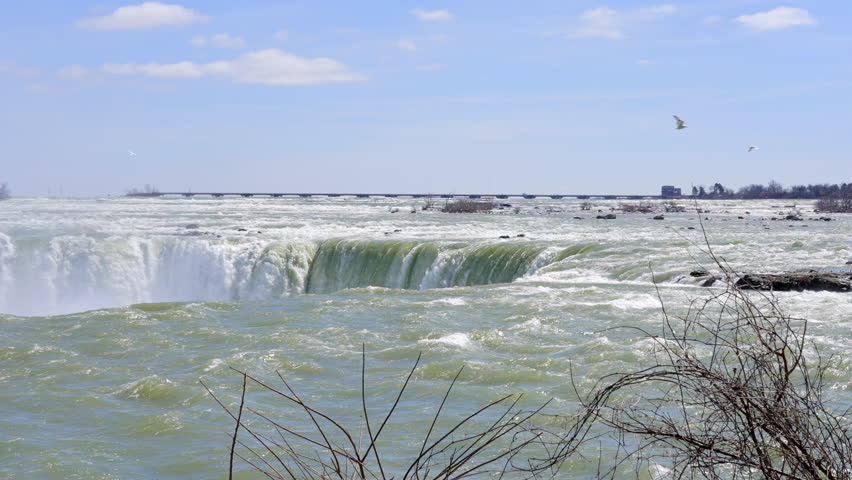 Establishing shot of majestic Niagara Falls with snow and icy at mountain background in Toronto, Canada, North America. Day time on March 2022. ProRes 422 HQ.