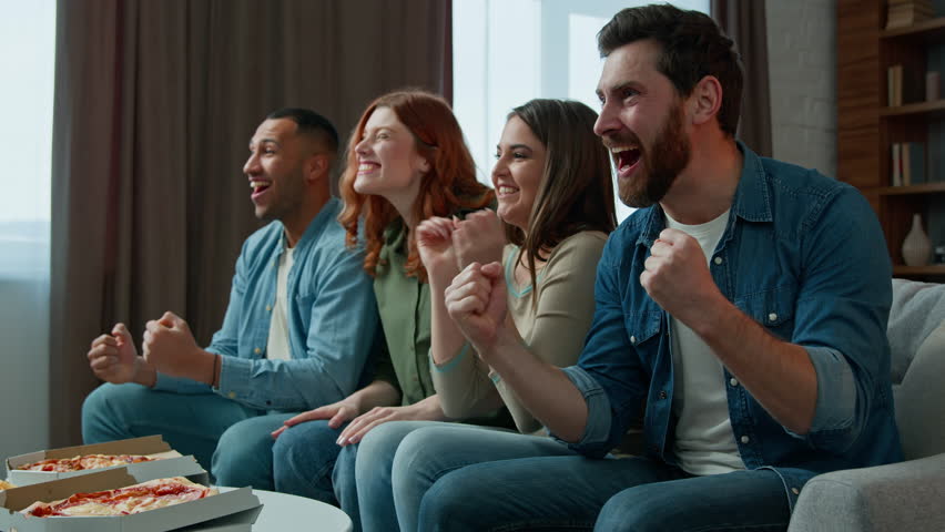 Excited football fans diverse ethnic friends multiracial men women watch tv sport soccer game celebrate goal favorite team win championship victory in television multiethnic people cheering screaming Royalty-Free Stock Footage #1100228841