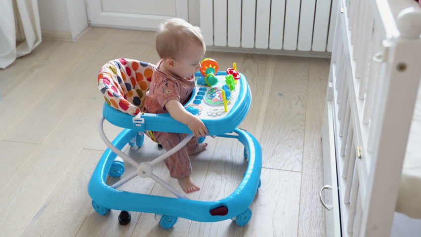 First steps of the girl in a baby walker