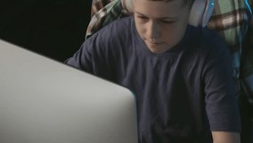 Teen boy plays computer game makes winning gesture. Kid playing video game at home. Home leisure.