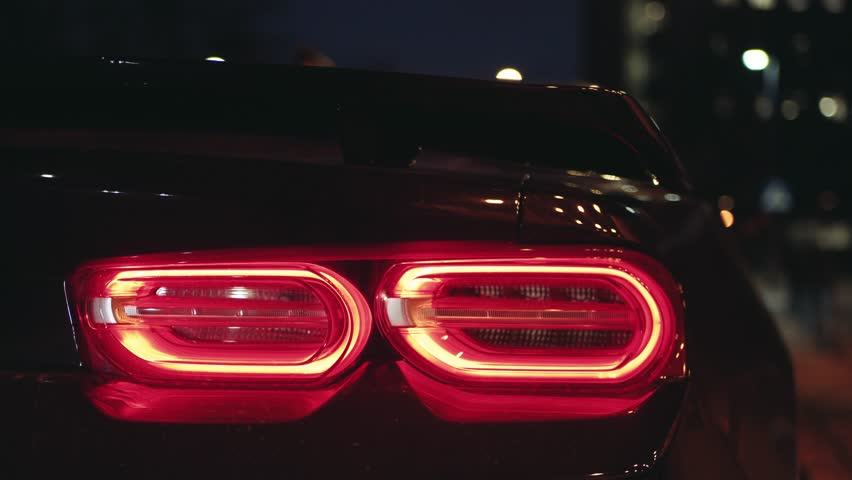 Black sports car tail light glowing in the dark of a night city | Shutterstock HD Video #1100237723