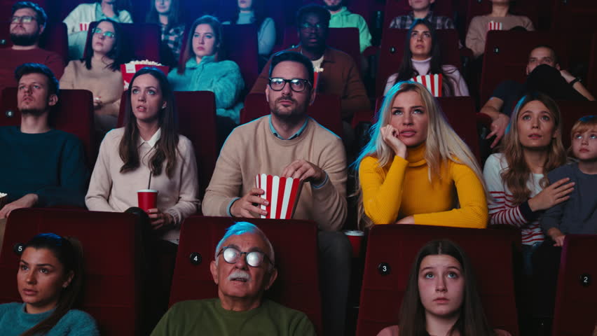 A young joyful Caucasian couple is in a movie theater laughing at a funny movie they are watching on the big screen. Royalty-Free Stock Footage #1100239831