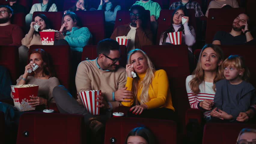 A young Caucasian woman is in the cinema watching a sad movie and being consoled by her boyfriend. | Shutterstock HD Video #1100239845