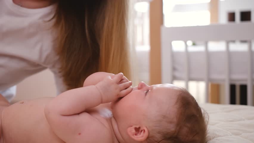 woman mother play and kissing baby infant on cheek softly on bed. baby happy  | Shutterstock HD Video #1100240469