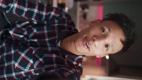 Young man influencer social media streaming video calling in online chat using smartphone home. Happy biracial teen guy talking camera holding phone recording promo vlog. 9x16 vertical view. UGC - Powered by Shutterstock - Get 15% off with code: PIKWIZARD15