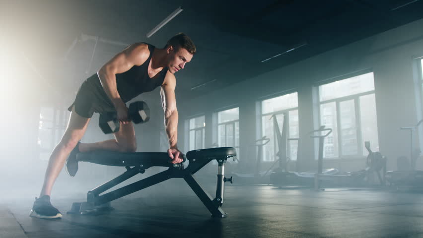 Close-up view of caucasian man in black sportswear lifting his arm to waist level. Portrait of focused sportsman training his biceps while working out alone in the gym. High quality 4k footage Royalty-Free Stock Footage #1100242339