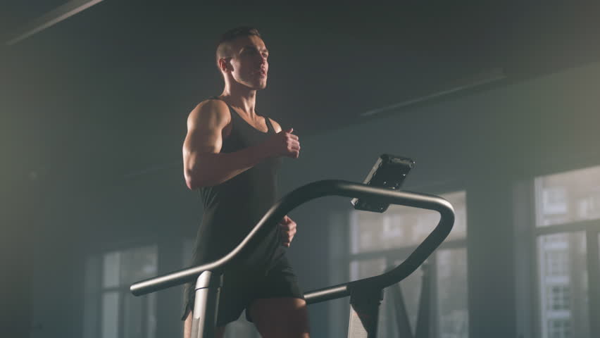 Close-up view of active, caucasian sportsman having intensive cardio workout to burn calories. Portrait of young, caucasian man jogging on gym machine. High quality 4k footage | Shutterstock HD Video #1100242371