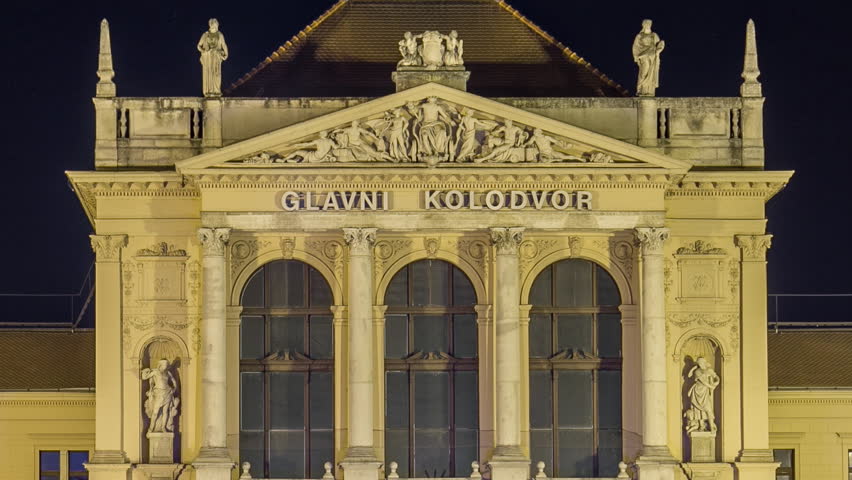 People on the Tomislav Square in front of Main Railway Station night timelapse, main hub of Croatian Railways network. Traffic on the road. Zagreb, Croatia