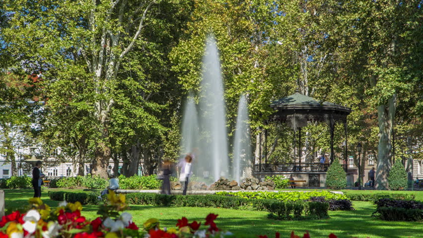 Fountains in Zrinjevac, one of the oldest parks in city timelapse. Zagreb, Croatia. People sitting around and making photos